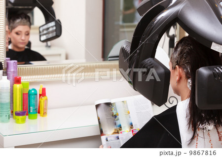 Woman reading magazine in hair beauty salon. By hairdresser. Woman reading magazine in hair beauty salon. By hairdresser. 9867816