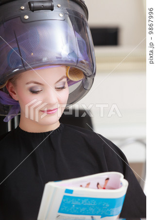 Woman client curlers in hair reads magazine hairdressing beauty salon. Woman client curlers in hair reads magazine hairdressing beauty salon. 9867996