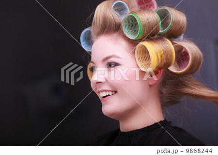 Blond girl hair curlers rollers by hairdresser in hairdressing salon 9868244