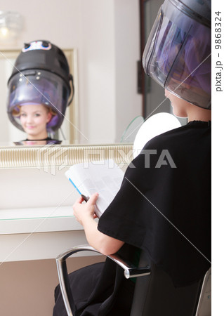 Woman client curlers in hair reads magazine hairdressing beauty salon. Woman client curlers in hair reads magazine hairdressing beauty salon. 9868324