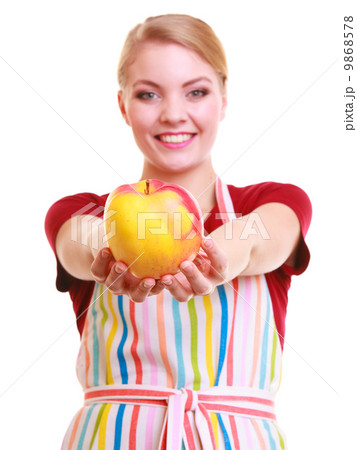 Happy housewife or chef in kitchen apron showing apple isolated Happy housewife or chef in kitchen apron showing apple isolated 9868578