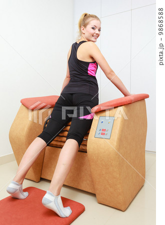 Girl in sportwear using relax massage equipment healthy spa salon 9868588