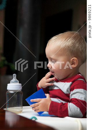 baby boy playing with bottle and mug indoor 9869211