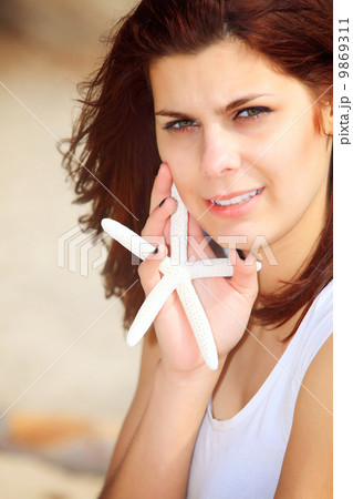 young woman on seacoast with shell in hand 9869311
