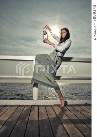 Girl on pier with kerosene lamp 9869348