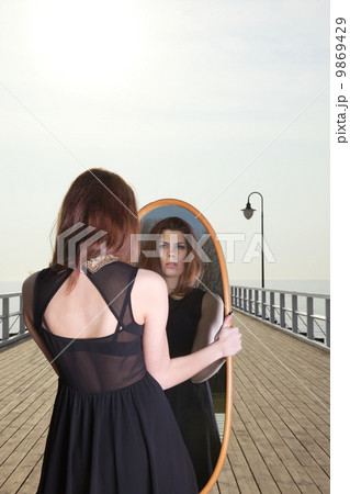 thoughtful woman looks at the reflection in mirror 9869429