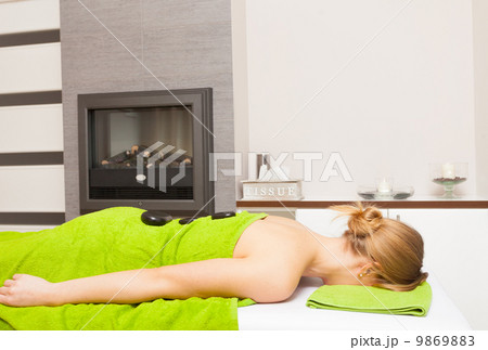 Spa salon. Woman relaxing having hot stone massage. Bodycare. 9869883