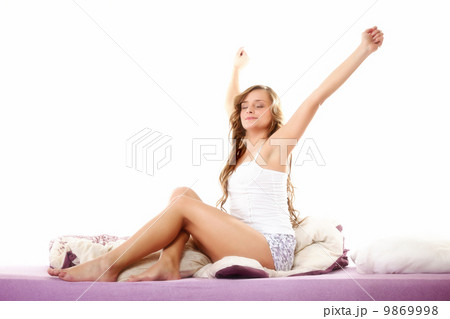 woman waking up in bed and stretching her arms up woman waking up in bed and stretching her arms up 9869998