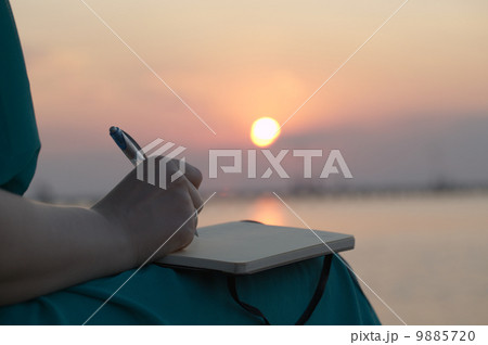 Woman writing in her diary at sunset Woman writing in her diary at sunset 9885720