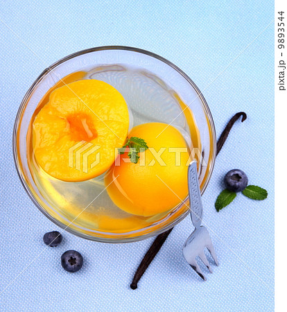 Peach compote in glass bowl with fork, blueberries and vanilla 9893544