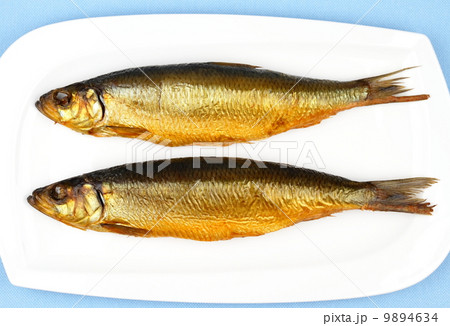 Two kippers, smoked herring on white plate 9894634