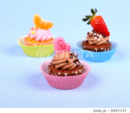 Three appetizing cupcakes with heart, tangerine, and strawberry Three appetizing cupcakes with heart, tangerine, and strawberry 9895145