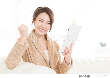 部屋でタブレットを見る女性  9896862