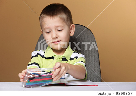Young cute boy draws with color pencils 9899357