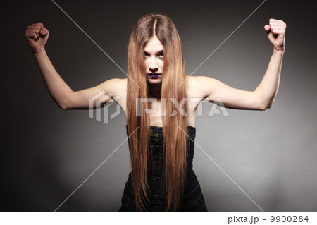 Sad girl with long hair and creative makeup showing her muscles 9900284
