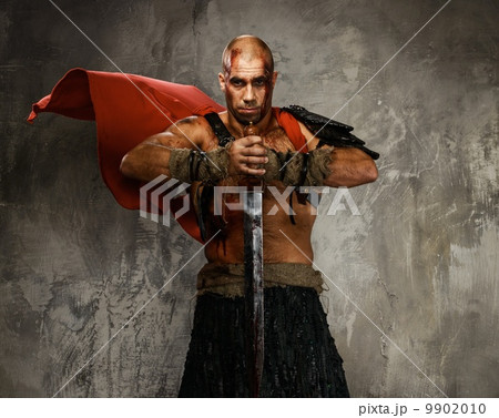 Wounded gladiator with  sword covered in blood isolated on grey 9902010