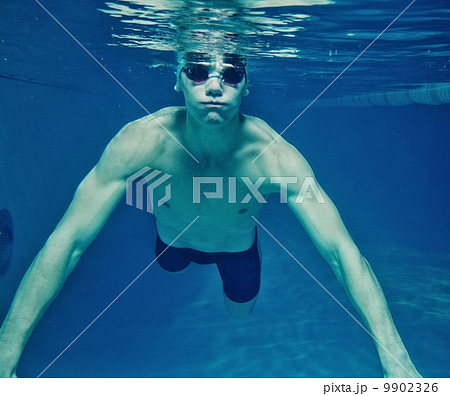 Man in swim cap and googles under water in swimming pool Man in swim cap and googles under water in swimming pool 9902326