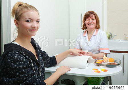 Beautician with file filing nails female client in beauty salon 9915963