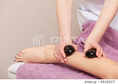 Beauty salon. Woman getting spa hot stone legs massage 9916027