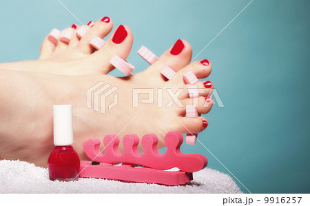 foot pedicure applying red toenails on blue 9916257
