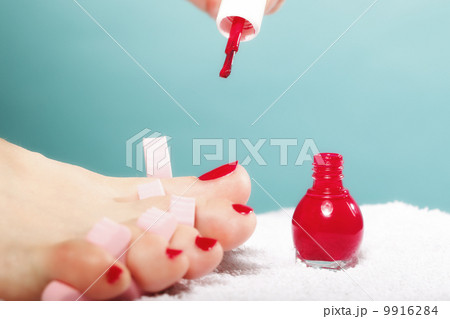 foot pedicure applying red toenails on blue foot pedicure applying red toenails on blue 9916284