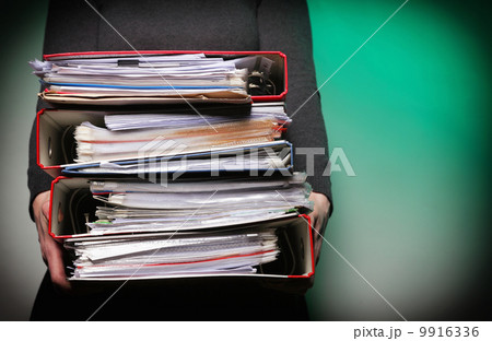Female office worker carrying a stack of files Female office worker carrying a stack of files 9916336