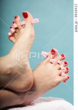 foot pedicure applying red toenails on blue foot pedicure applying red toenails on blue 9916417