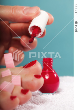 foot pedicure applying red toenails on blue 9916559