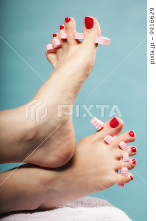foot pedicure applying red toenails on blue foot pedicure applying red toenails on blue 9916629