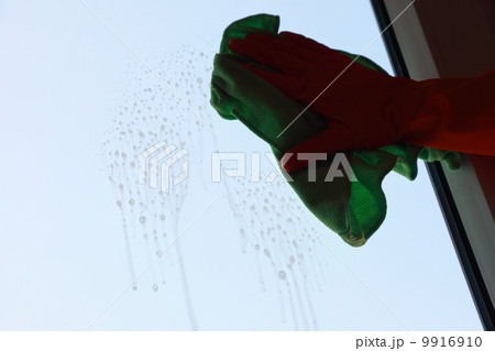 Gloved hand cleaning window with rag 9916910