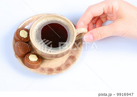 chocolate pralines, cup, black coffee and female hand on white 9916947
