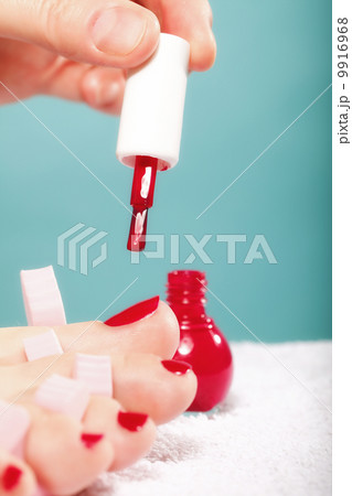 foot pedicure applying red toenails on blue 9916968