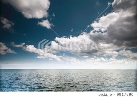 Cloudy blue sky above a surface of the sea 9917590
