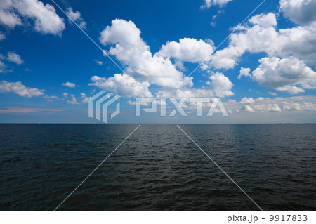 Cloudy blue sky above a surface of the sea 9917833