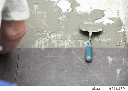 Construction worker is tiling at home tile floor adhesive Construction worker is tiling at home tile floor adhesive 9918870