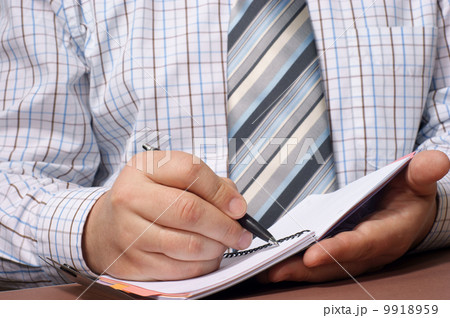 Close-up of a businessman's hand with a pen writing something. 9918959