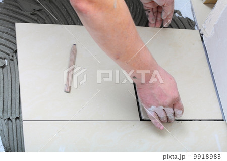 Construction worker is tiling at home, tile floor adhesive Construction worker is tiling at home, tile floor adhesive 9918983
