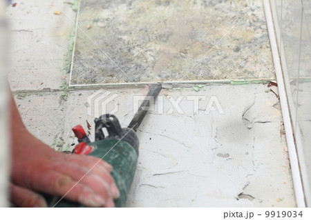 manual worker disassembling old floor tiles 9919034