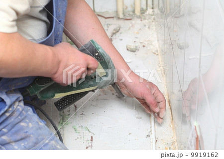 manual worker disassembling old floor tiles 9919162