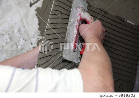 tiler at work bonding of floor tile adhesive 9919202