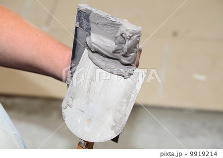 Hand holding a bucket trowel with cement mortar Hand holding a bucket trowel with cement mortar 9919214