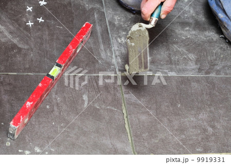 Construction worker is tiling at home tile floor adhesive Construction worker is tiling at home tile floor adhesive 9919331