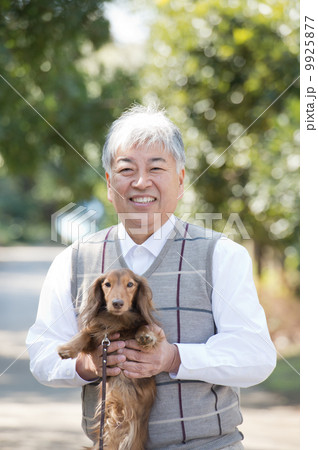 犬を抱っこするシニア 9925877