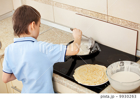 Child bakes pancakes 9930263