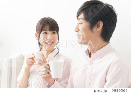 コーヒーを飲みながら笑顔で会話をするカップル 9936562