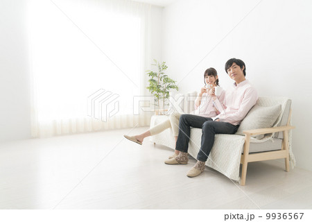 ソファーに座り、コーヒーを飲みながら会話をするカップル 9936567