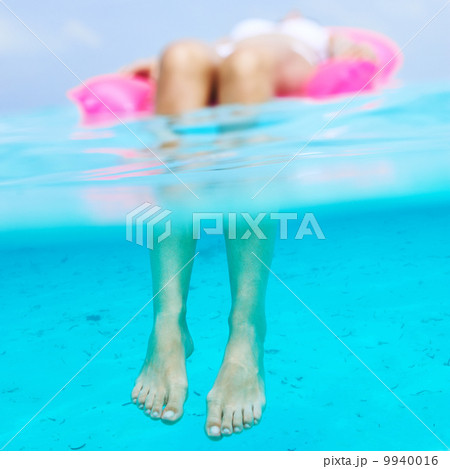 Woman relaxing on inflatable mattress, view from underwater Woman relaxing on inflatable mattress, view from underwater 9940016