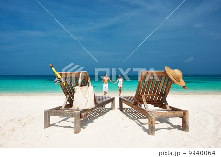 Couple in white running on a beach at Maldives 9940064