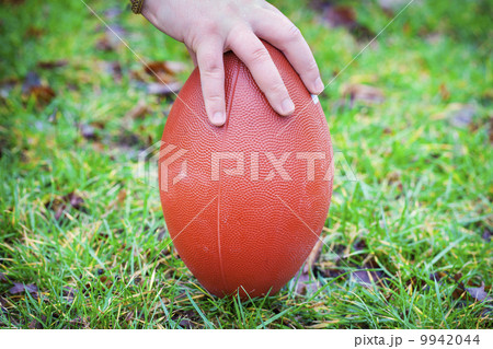 Hand on rugby ball on green grass background Hand on rugby ball on green grass background 9942044