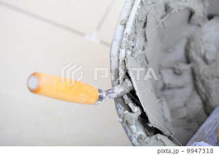 Dirty trowel and bucket on building site. Renovation at home 9947318